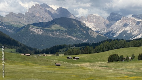 Fotografía Scenic Dolomite peaks above green alpine meadows and traditional mountain cabins at Alpe di Siusi, Italy