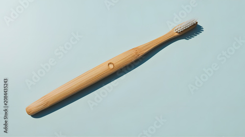 a tooth brush of brown colour lying on sky blue color background