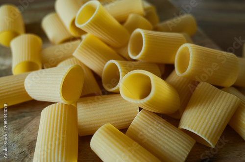 Various pieces of uncooked pasta scattered on a wooden surface in a kitchen setting during daylight hours