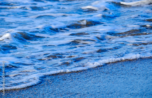 Принти на полотні Multiple consecutive small ocean waves rolling continuously towards the shore creating beautiful parallel lines of frothy white water across the shallow coastal marine environment