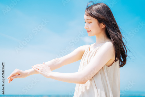 Photos 海で日焼け止めを塗る若いアジア人女性