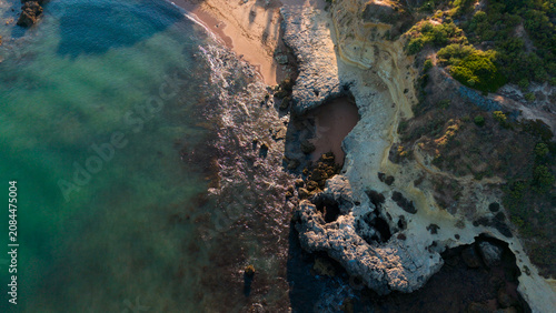 serene coastal landscape with wave interaction on rocky shoreline, aerial view of ocean and sand, beach and cliff setting, greenish-blue and brown tones, nature photography, vacation, Praia dos Aveiro
