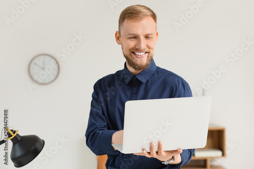 Smiling man using laptop in...