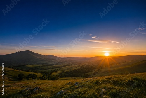 Golden rays of dawn breaking over the horizon into a deep blue pre-dawn sky.