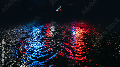 Red and Blue Emergency Lights Reflecting on Wet Dark Asphalt Street at Night