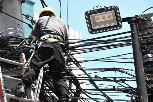 Canvastavla A linesman from power company working above ground stepping an a ladder and on wires during daytime