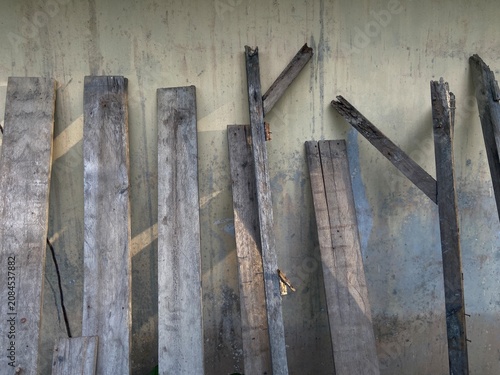 Εκτύπωση καμβά Abandoned wooden planks lean against a dirty concrete wall in a desolate outdoor setting