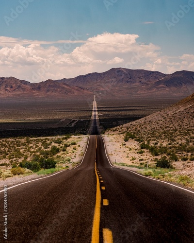 Konstfotografi Iconic endless straight desert highway with yellow dashed center line stretching