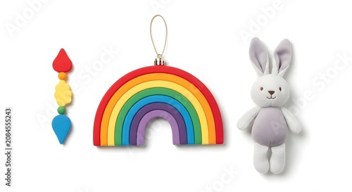 Three charming decorative ornaments: a rainbow-colored beaded strand, a vibrant rainbow arch, and a soft gray plush bunny.
