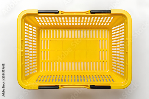 Overhead view of a vibrant yellow plastic shopping basket on png, shopping basket, yellobasket, plastic basket, store basket, supermarket basket, shopping container, retail, grocery, market, container