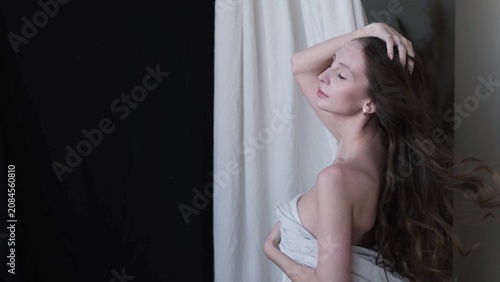 Portrait of a beautiful brunette with long hair on a fabric background in the studio. Beautiful natural woman posing for the camera