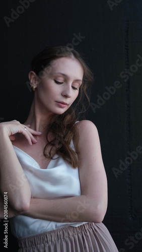 Portrait of a beautiful young girl on a dark studio background. Beautiful natural woman posing for the camera