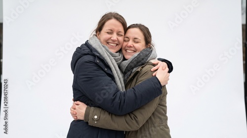 Two women hugging and smiling warmly with eyes closed