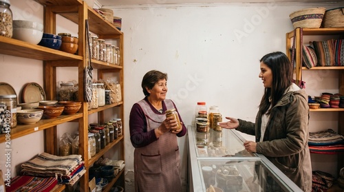Shopkeeper assisting customer in a small store selling grains and textiles