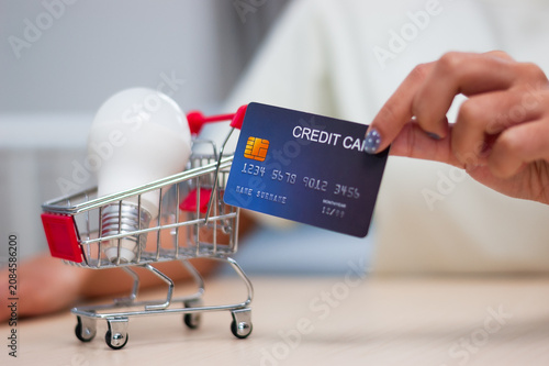 Exploring modern home solutions credit card in hand light bulb ready for purchase in cart