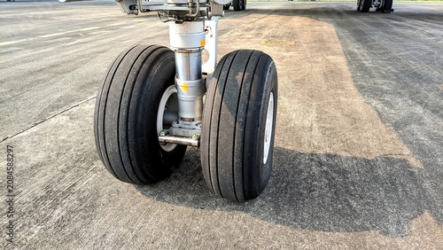 Close-up front view of an aircraft nose landing gear with dual tires parked on the airport apron