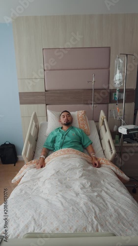 Male patient resting and recovering in a modern hospital room with IV drip, medical bed, and healthcare equipment, representing treatment, recovery, and medical care.