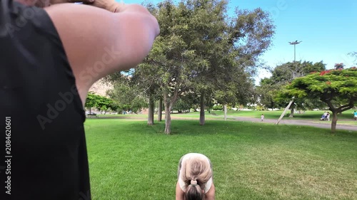 A blonde woman training in a park with her coach