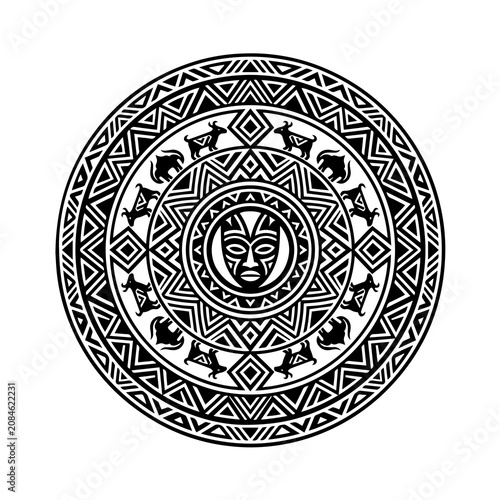Black and white circular tribal mandala pattern featuring a central mask surrounded by geometric shapes and animal silhouettes
