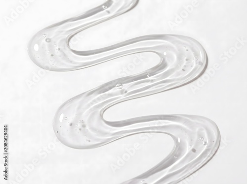 Transparent cosmetic gel serum texture swirled in a wavy liquid pattern with small air bubbles in bright studio lighting