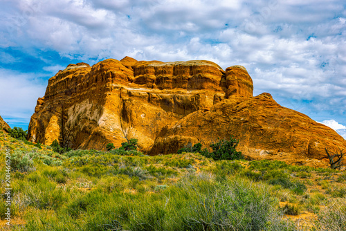 Fotografija High-angle view of a large monolithic sandstone rock structure rising above desert plains in Devils Garden