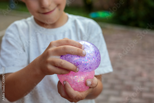 фотографія Smiling little boy playing with a glittery dumpling shaped squishy toy outdoors,