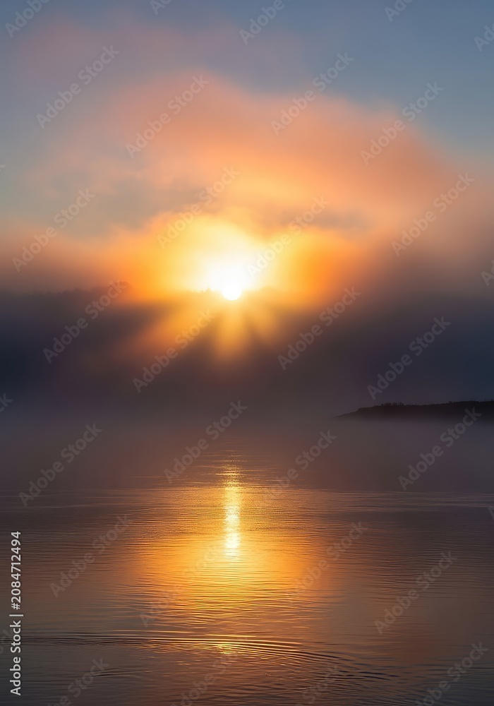 Obraz premium Thick morning mist rolls across the surface of a tranquil river as the rising sun creates a soft golden glow through the dense grey fog, mist, landscape, sunbeams
