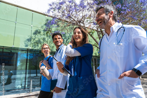 Obraz na plátně Diverse medical team walking and laughing in front of hospital