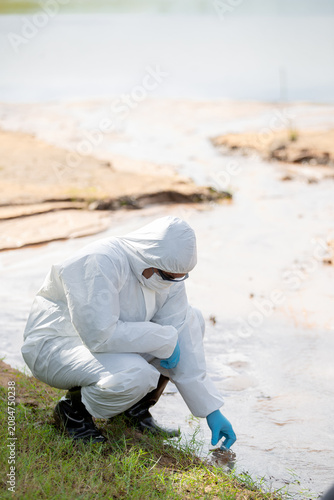 фотографія Ecologist in protective gear collecting water samples for environmental research