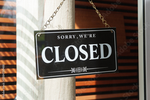 Closed storefront sign displayed at business entrance with copy space