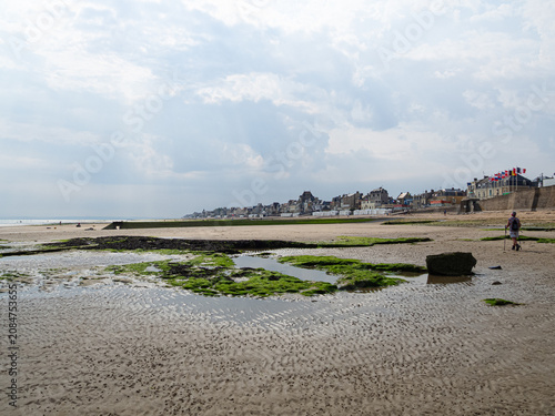 Playa de Saint-Aubin-sur-Mer, vista del paisaje de nubes y mar sobre arena dorada con algas verdes, viajando en verano de 2022