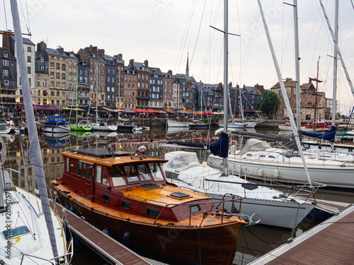 Vista del pintoresco puerto de Honfleur, donde se ven edificios al fondo y barcos recreativos en primer plano, viajando en verano de 2022 por la Normandía Francesa