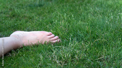 Close-up of a female bare foot lying on fresh green grass outdoors, symbolizing relaxation, nature connection, and summer freedom