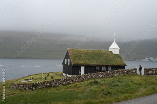 Historic turf-roofed Kaldbak Church with a visitor on Streymoy island, Faroe Islands