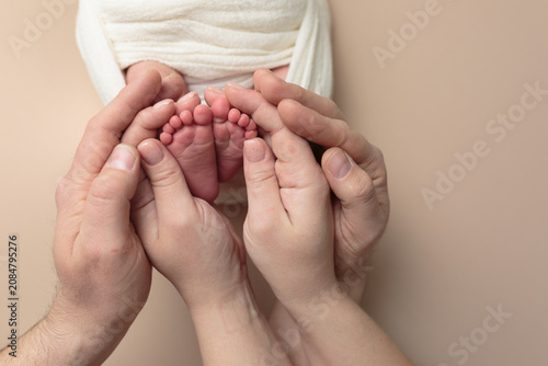 Newborn Baby Feet Held by Parents' Hands
