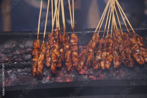 Принти на полотні Smoky chicken satay skewers grilling over hot charcoal, showcasing authentic Indonesian street food
