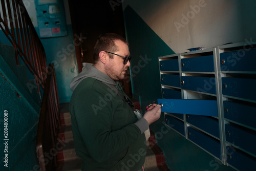 Man Checking Mail in Apartment Building Hallway