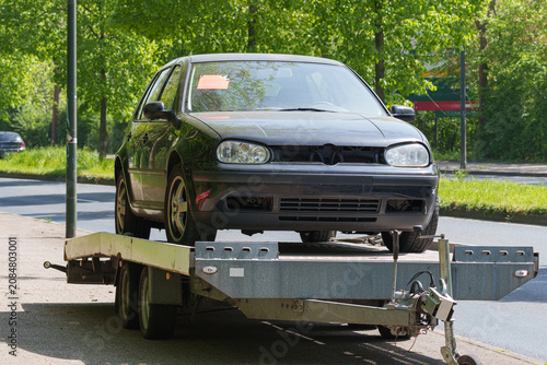 Passenger car secured on recovery trailer for roadside transport after breakdown