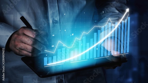 Photos A businessman uses a tablet to analyze financial data, showcasing digital graphs that illustrate market trends and growth projections in a modern office