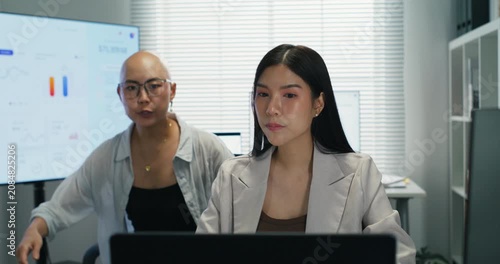 Professional Asian female employee working on a computer. Focused on financial analysis, investment planning, and corporate strategy in a modern, professional workplace environment.