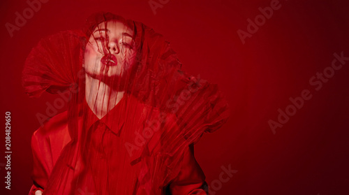 Portrait of a woman with red veil over her face in red lighting