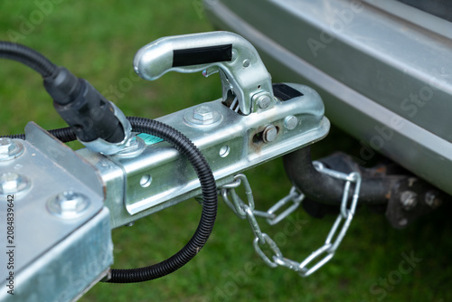 Connected trailer hitch to a car. A metal trailer coupling mechanism is securely fastened to a car tow ball, symbolizing safety, preparation, and readiness for movement