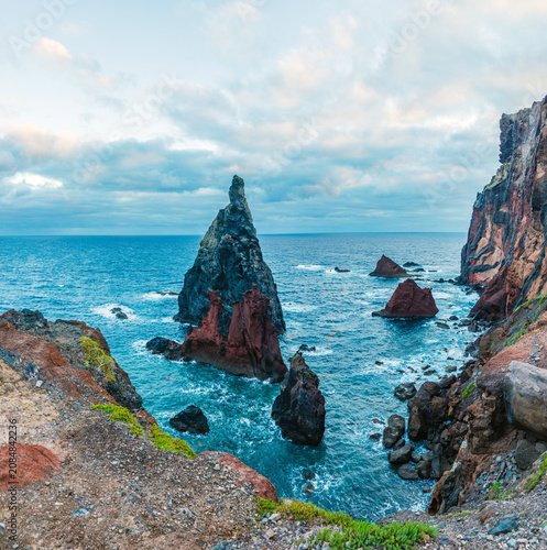 Sharp volcanic sea stacks rising dramatically from the blue ocean waters near the rocky coast of Ponta de Sao Lourenco, Madeira, Portugal.