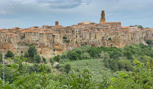 Aerial view of Pitigliano, a historic town built on a volcanic tuff cliff, featuring stone buildings, terracotta rooftops, and a bell tower in Pitigliano, Tuscany, Italy.