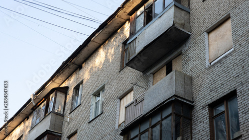 Bilde på lerret Old grey brick residential building with enclosed and boarded windows, concrete balconies, overhead power lines