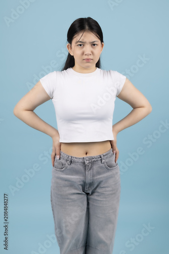 Confident young Asian woman standing with hands on hips looking at camera