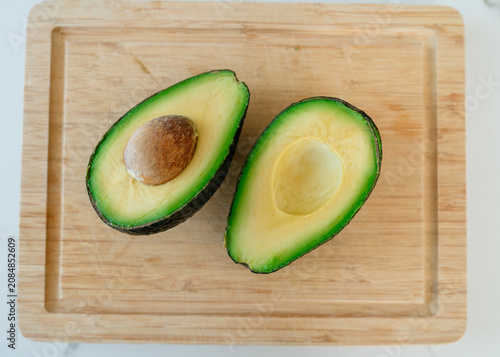 avocado halves sliced and displayed on wooden cutting board, fresh and natural, top-down perspective, commercial food photography, healthy eating, green and yellow accents.