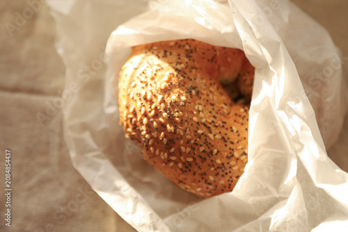 Foto Sesame and poppy seed bagel in white paper bag