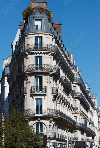 Striking close-up of a curved corner Haussmann building on the Rue du Quatre-Septembre in Paris, its stacked ornate wrought-iron balconies sweeping elegantly around the rounded angle.