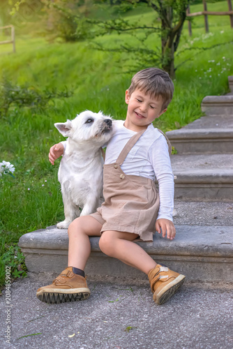 Foto Cheerful Caucasian toddler sitting on stone stairs outdoors, tenderly embracing